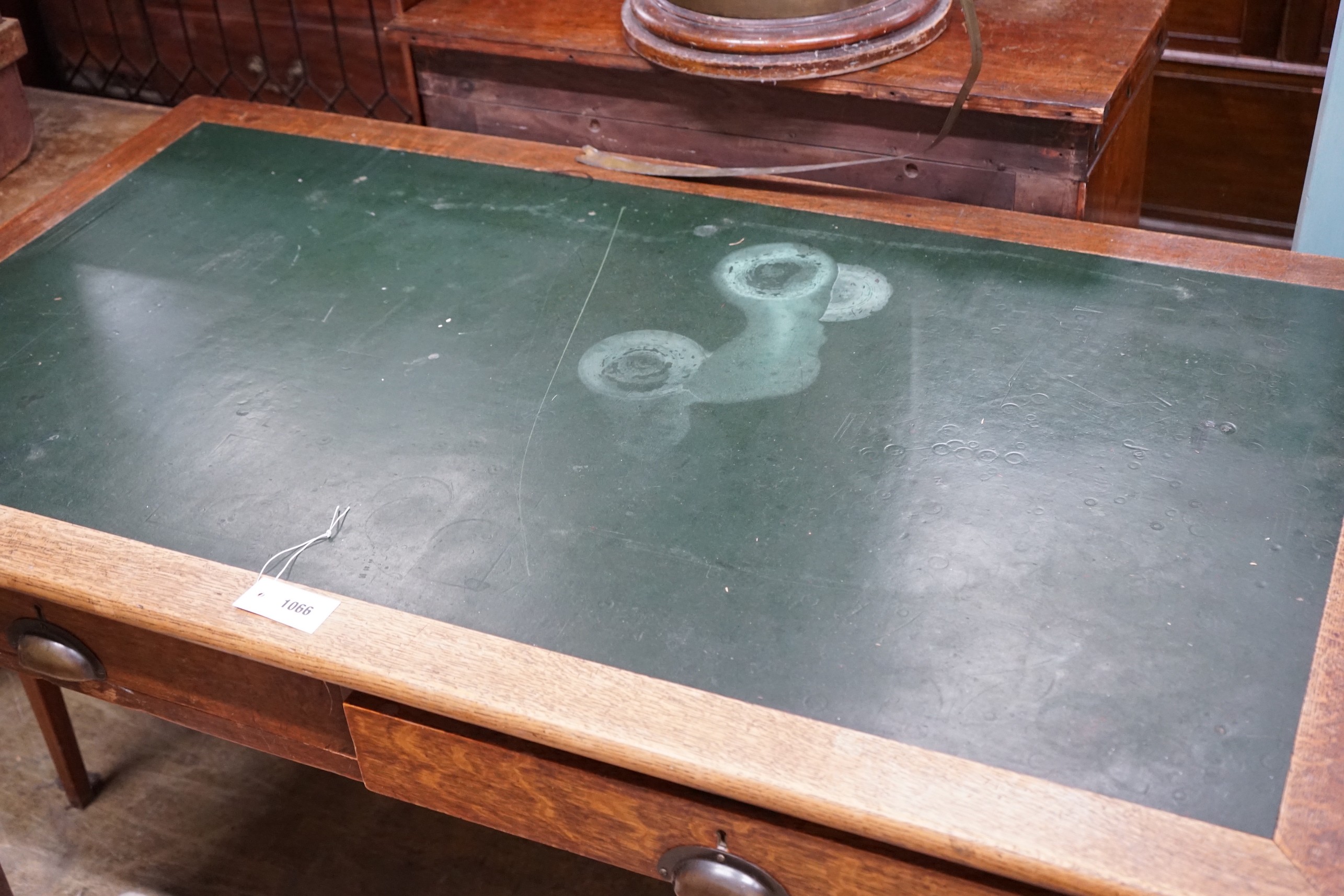 A 1920's oak two drawer writing table, width 136cm, depth 76cm, height 77cm